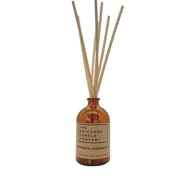 Aromatherapy diffuser with ratten reeds and an amber glass bottle on a white background.