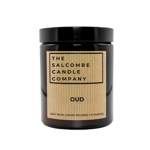 A 6-ounce soy wax candle in an amber glass jar with a black lid and a kraft paper label. The label reads 'THE SALCOMBE CANDLE COMPANY' and 'OUD'.